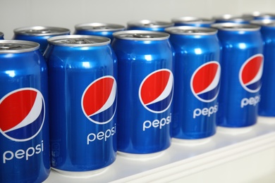 MYKOLAIV, UKRAINE - FEBRUARY 10, 2021: Cans of Pepsi on white shelf, closeup