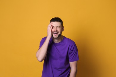 Photo of Handsome man laughing on yellow background. Funny joke