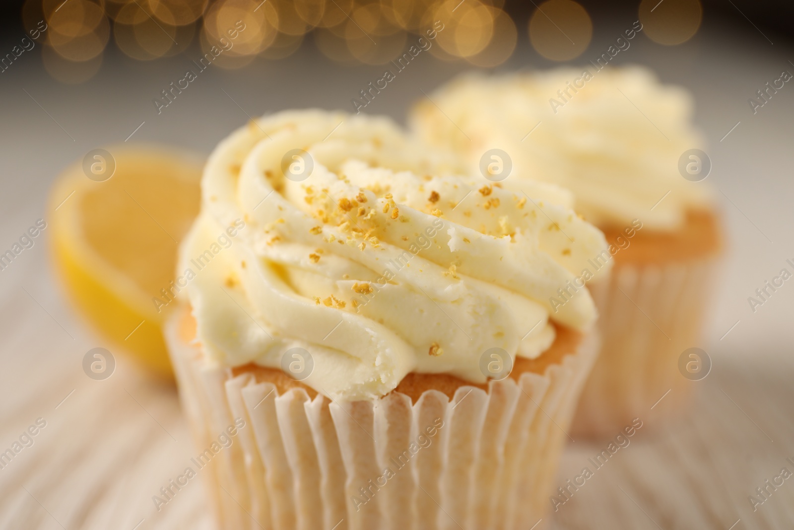 Photo of Tasty cupcake with cream and lemon zest on table, closeup