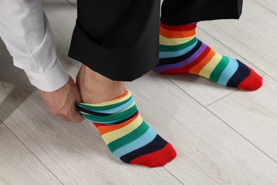 Photo of Man putting on colorful socks indoors, closeup