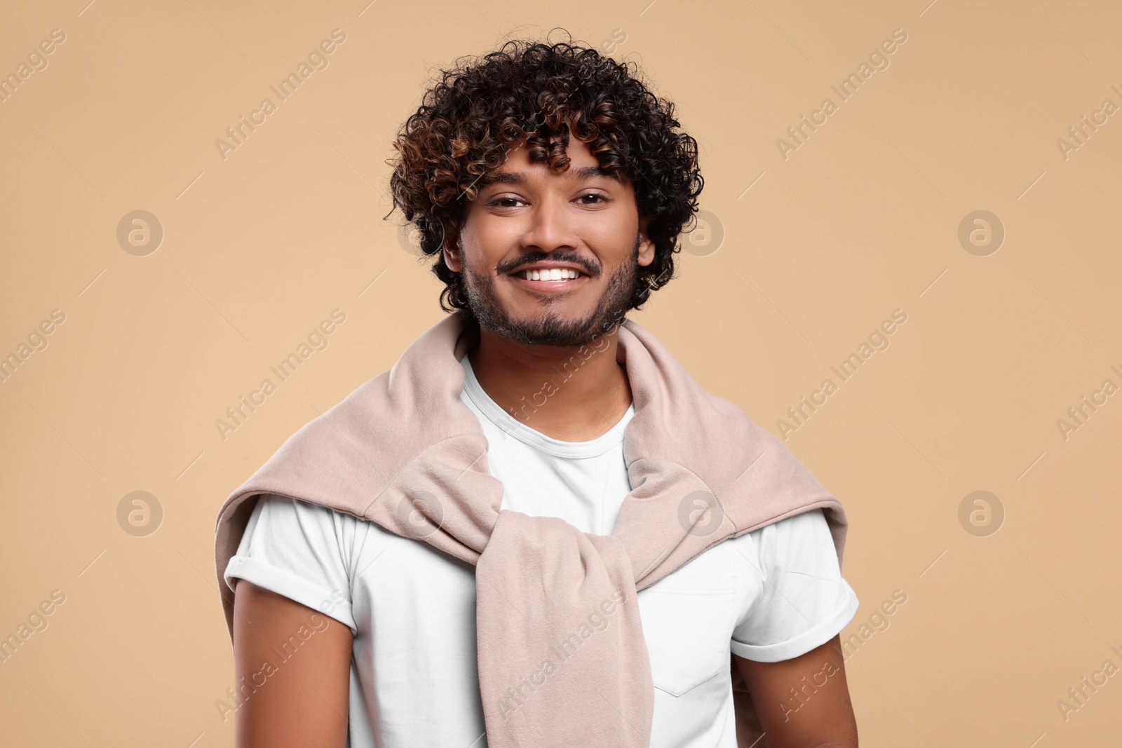 Photo of Handsome young smiling man on beige background