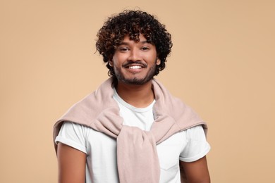 Handsome young smiling man on beige background