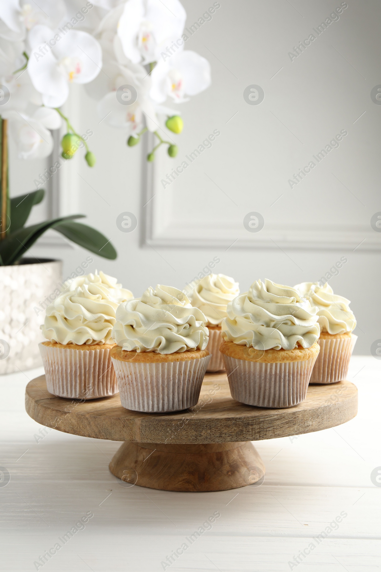 Photo of Tasty vanilla cupcakes with cream on white wooden table