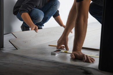 Photo of Workers installing new laminated flooring in room, closeup