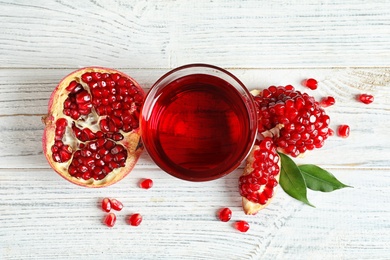 Glass of pomegranate juice and fresh fruits on wooden background, top view