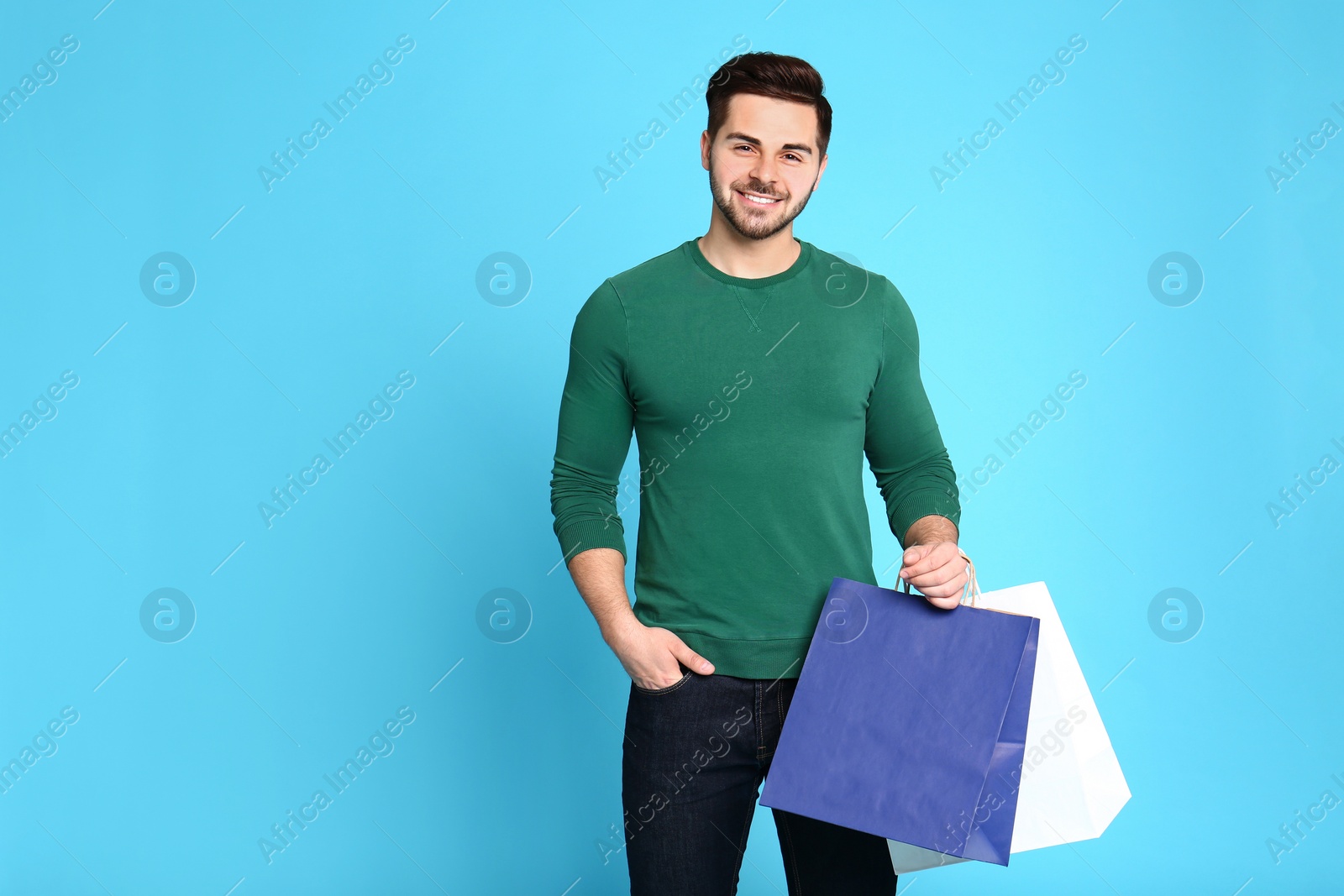 Photo of Portrait of young man with paper bags on blue background