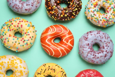 Photo of Delicious glazed donuts on turquoise background, flat lay