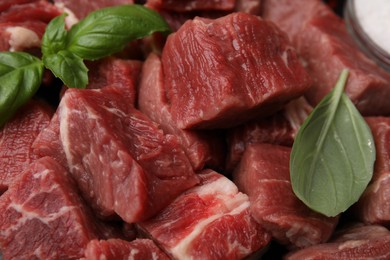 Photo of Cut fresh beef meat with basil leaves as background, closeup