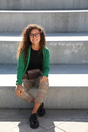 Photo of Beautiful African American woman with stylish waist bag on stairs outdoors