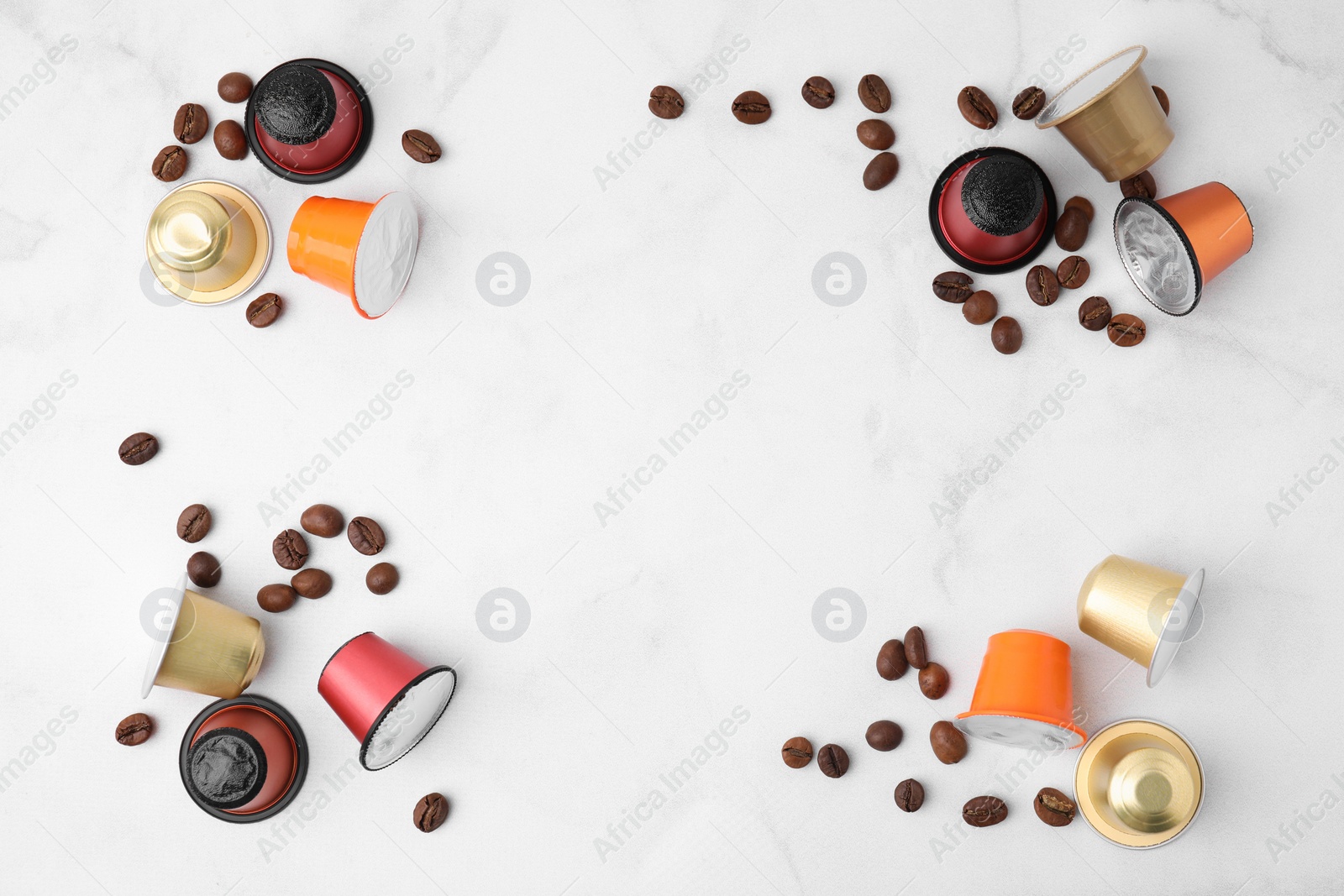 Photo of Many coffee capsules and beans on white marble table, flat lay. Space for text