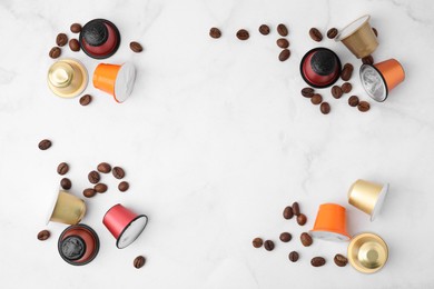 Many coffee capsules and beans on white marble table, flat lay. Space for text