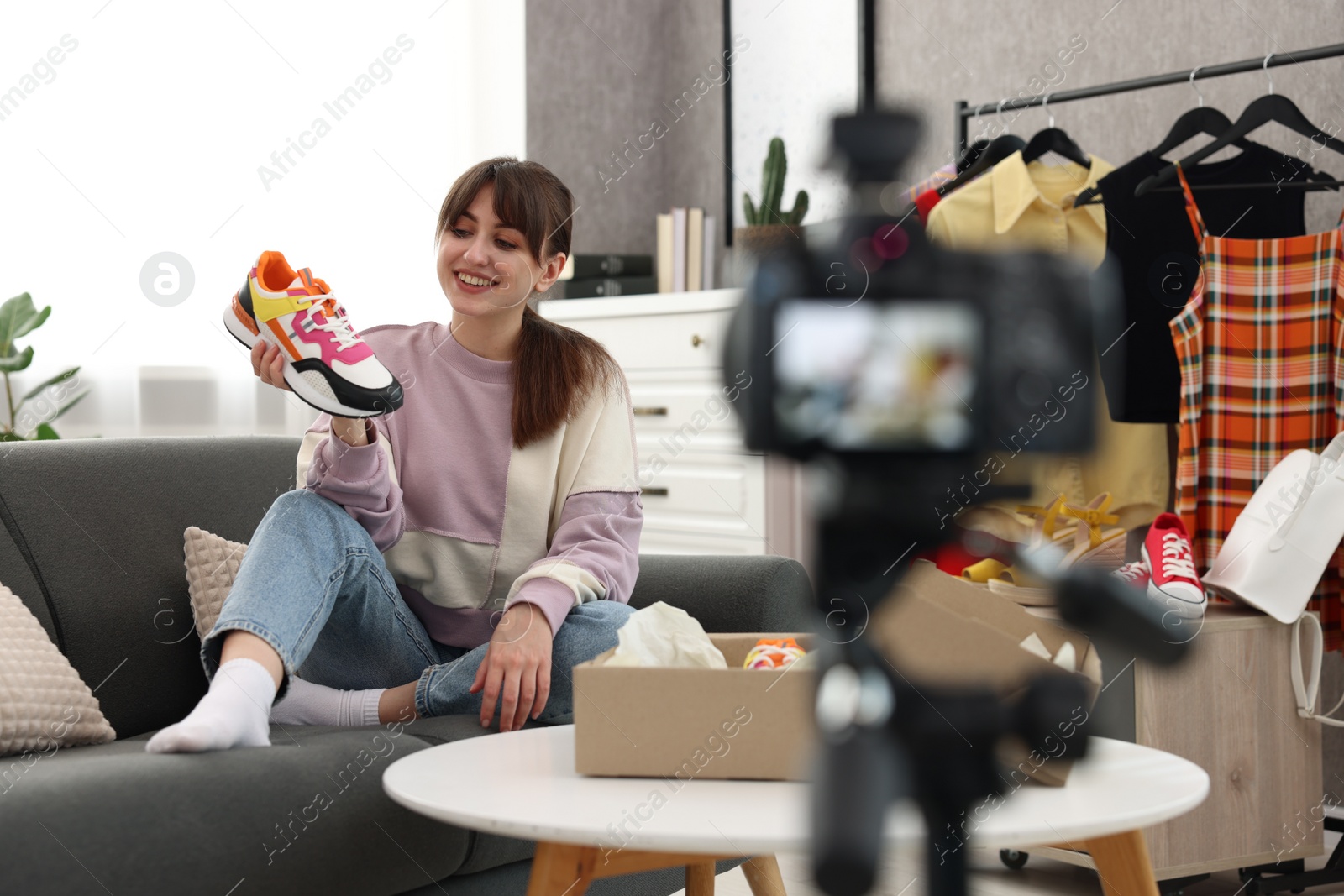 Photo of Smiling fashion blogger showing her shoes while recording video at home