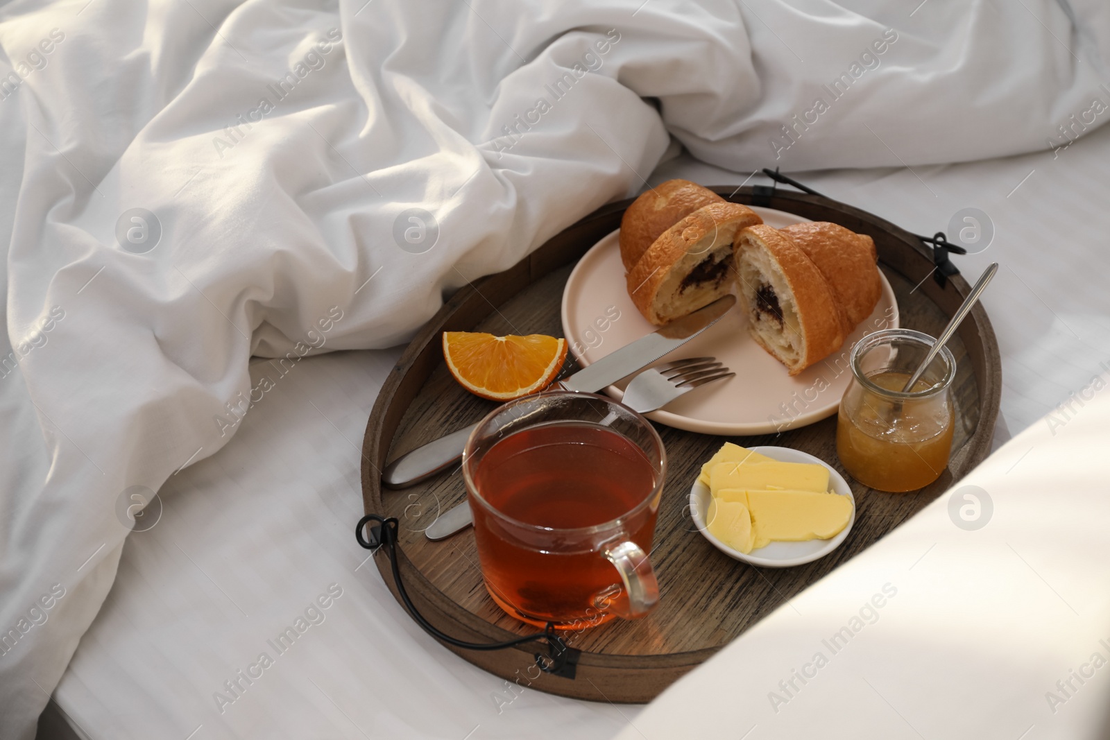 Photo of Tray with tasty breakfast on bed in morning