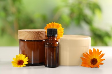 Photo of Different cosmetic products and beautiful calendula flowers on white table outdoors