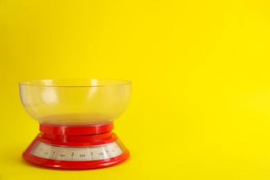 Photo of Kitchen scale with plastic bowl on yellow background, space for text