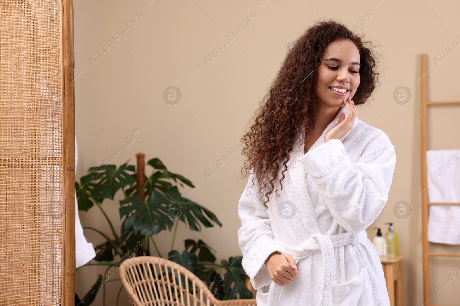 Photo of Beautiful African American woman in bathrobe at home, space for text