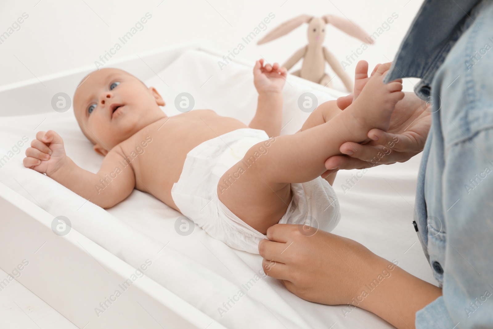 Photo of Mother changing her baby's diaper on table at home