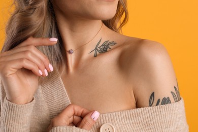 Photo of Beautiful woman with tattoos on body against yellow background, closeup