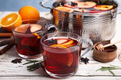 Tasty mulled wine with spices on white wooden table