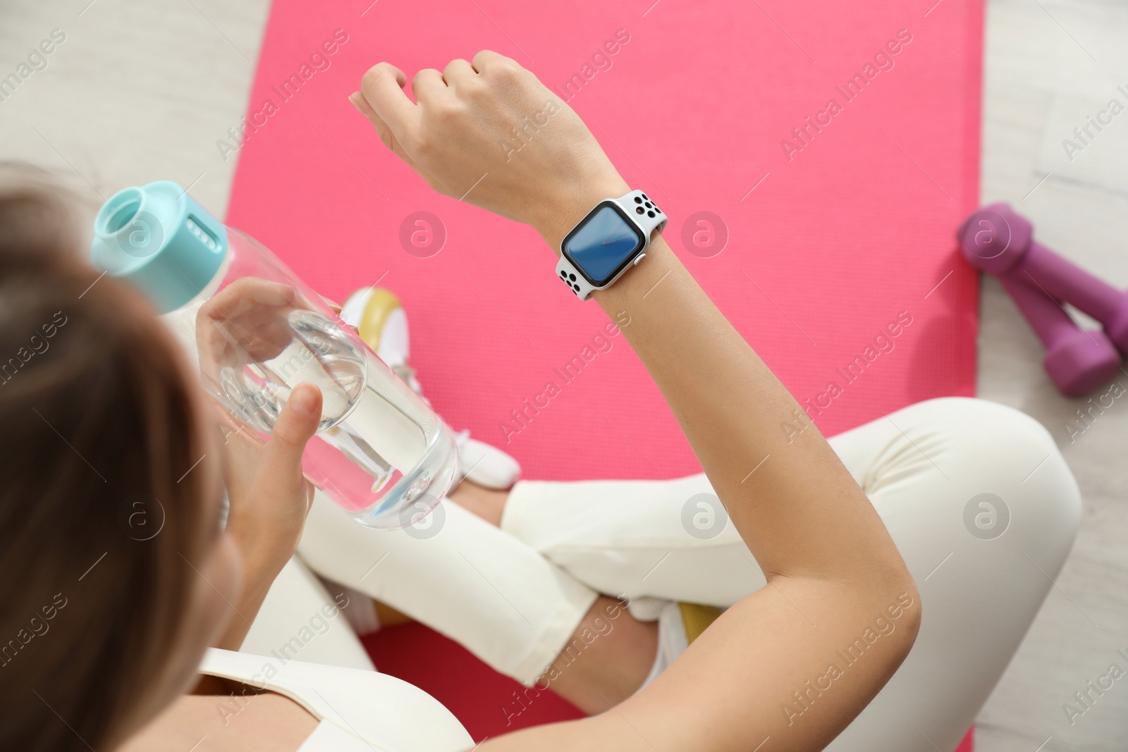 Photo of Young woman using smart watch during training indoors, above view