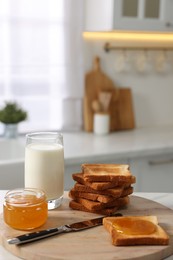 Breakfast served in kitchen. Crunchy toasts, honey and milk on table