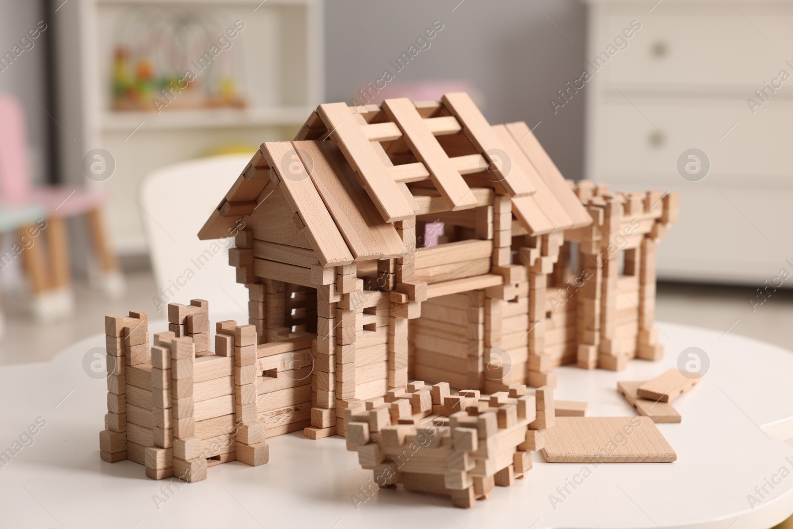 Photo of Wooden entry gate and building blocks on white table indoors. Children's toy