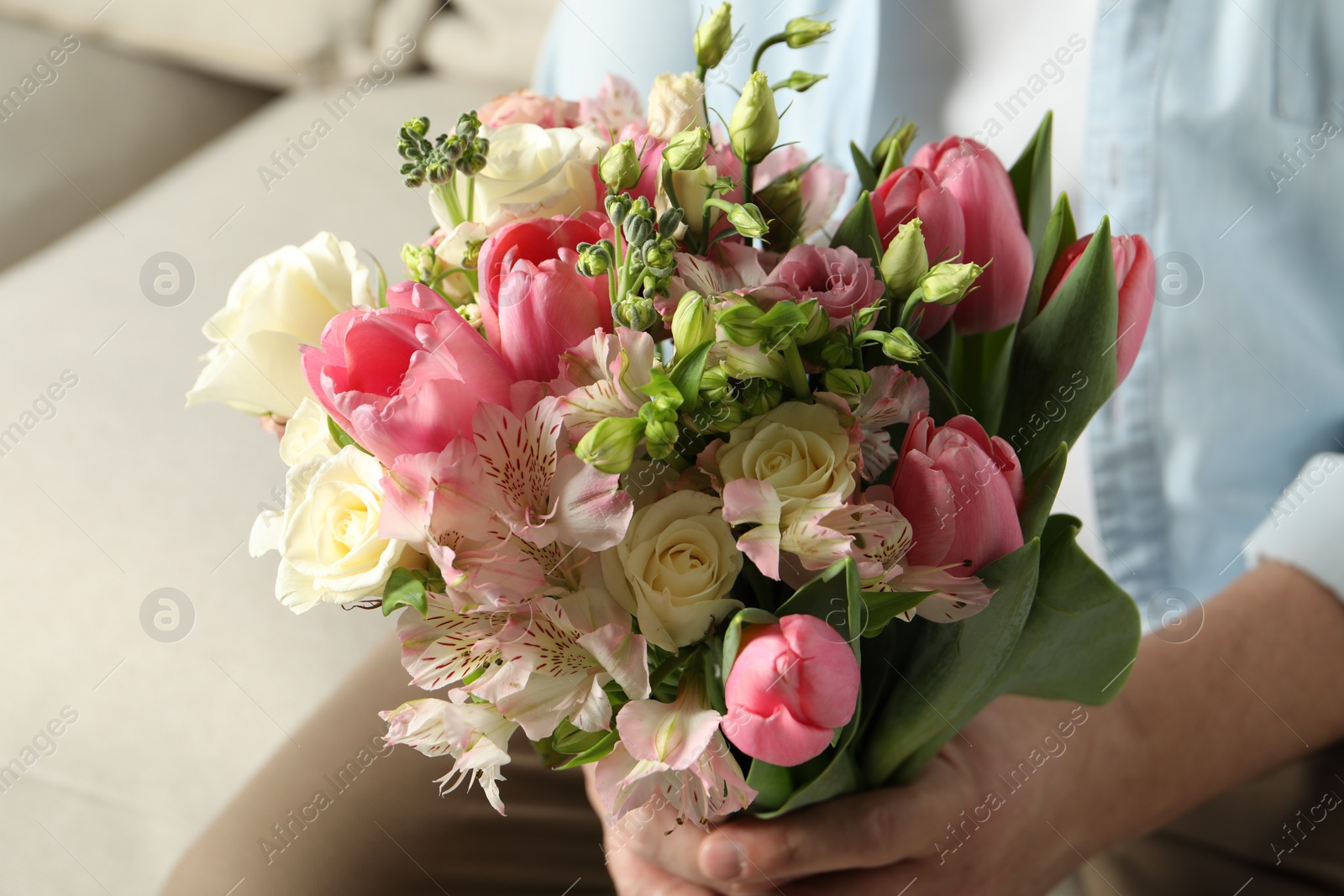 Photo of Man holding bouquet of beautiful flowers indoors, closeup