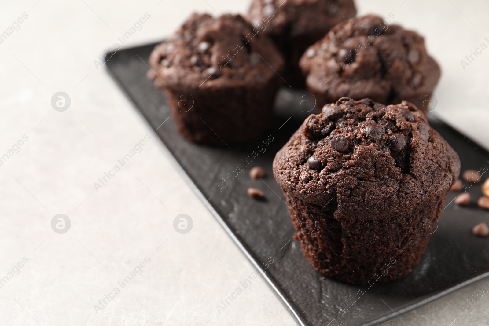 Photo of Delicious chocolate muffins on light table, closeup. Space for text