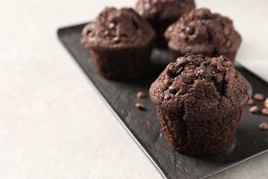 Delicious chocolate muffins on light table, closeup. Space for text