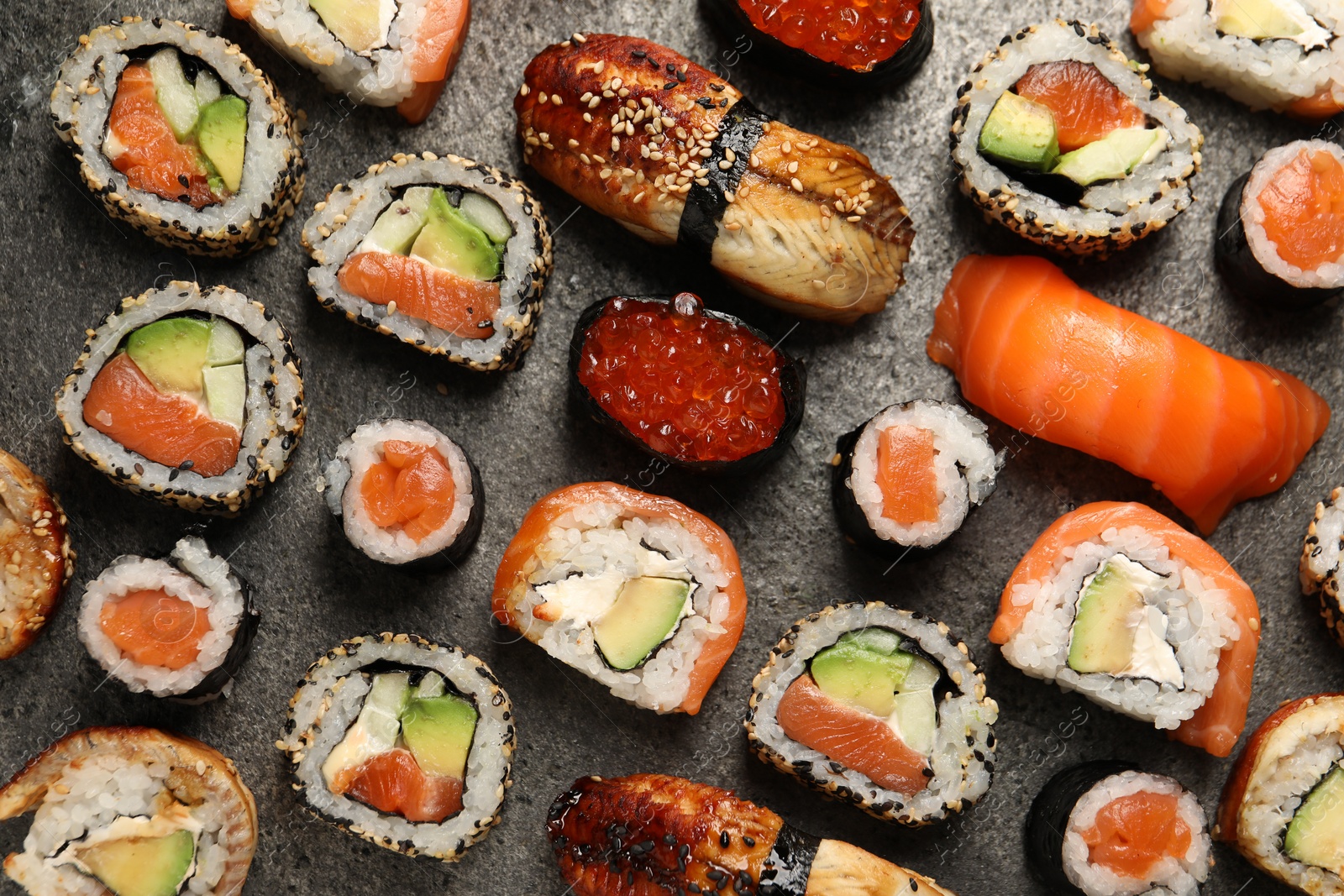 Photo of Different tasty sushi rolls on grey table, flat lay