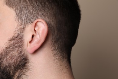 Photo of Man on grey background, closeup of ear