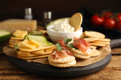 Photo of Different snacks with salted crackers on wooden table