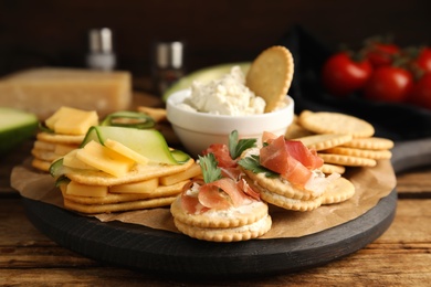 Different snacks with salted crackers on wooden table