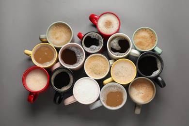 Many different cups with aromatic coffee on grey table, flat lay