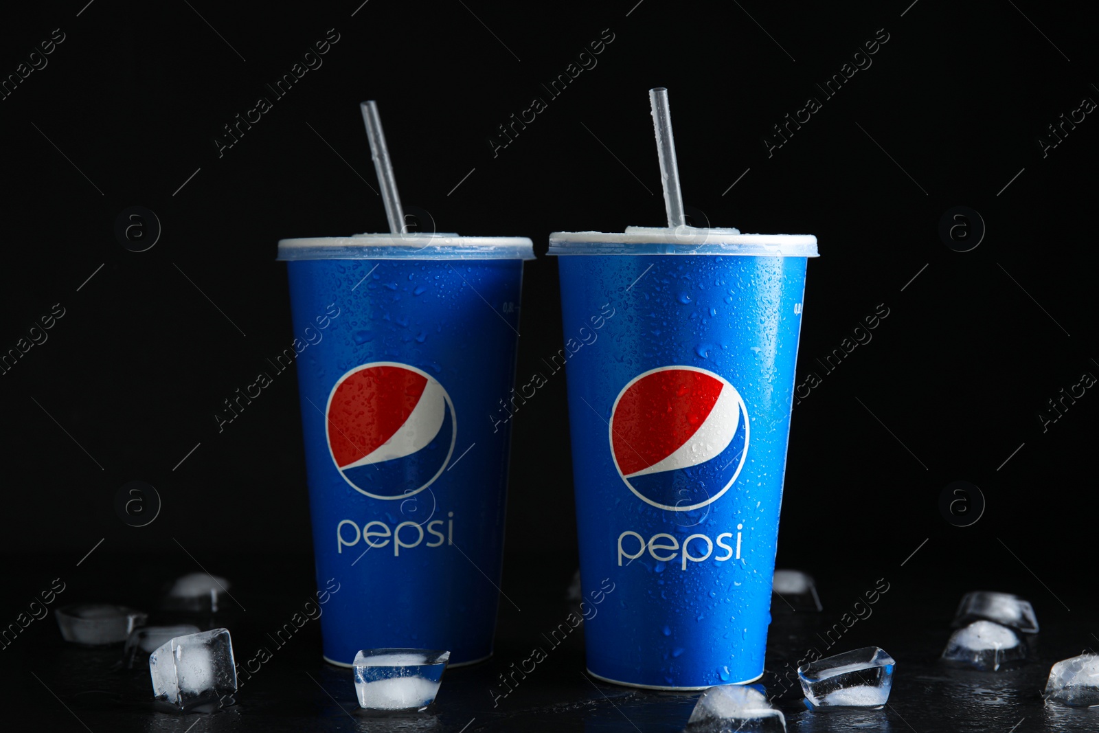 Photo of MYKOLAIV, UKRAINE - JUNE 9, 2021: Paper Pepsi cups with water drops and ice cubes on black background