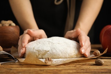 Photo of Woman with raw dough at wooden table, closeup