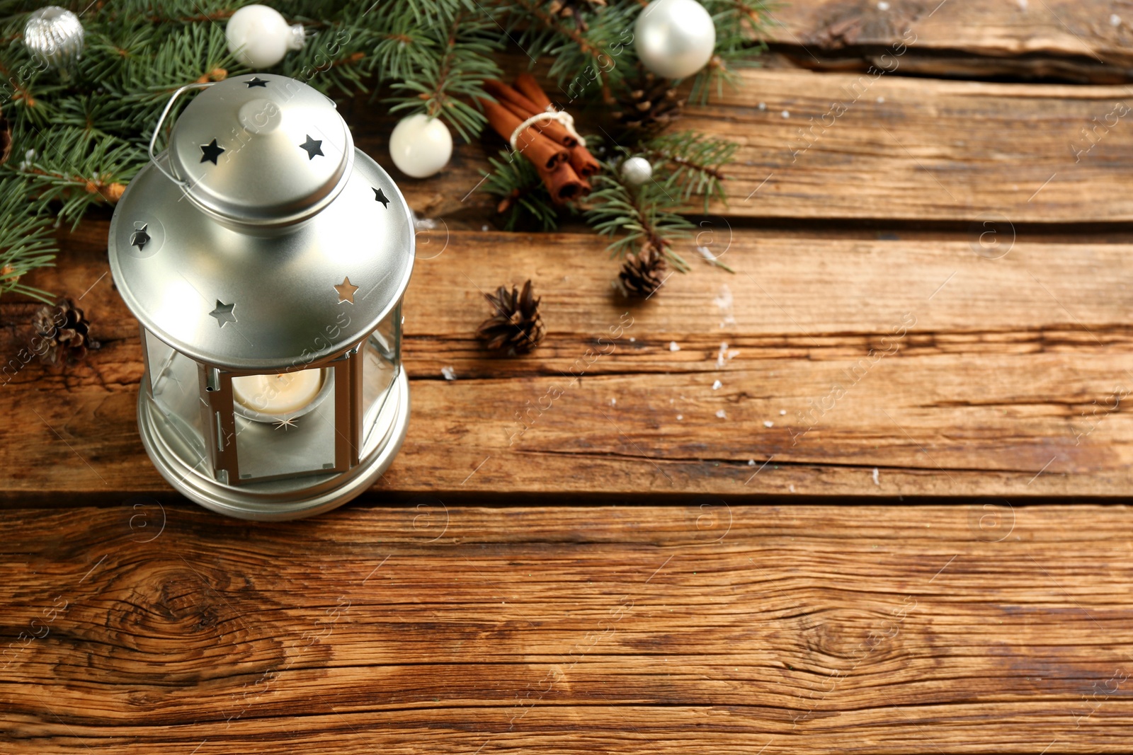 Photo of Christmas lantern with burning candle and festive decor on wooden table. Space for text