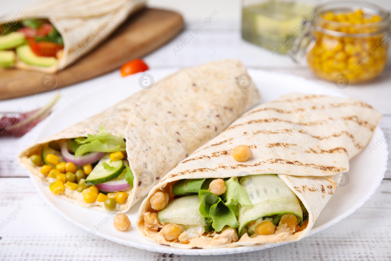 Photo of Delicious hummus wraps with vegetables on table, closeup