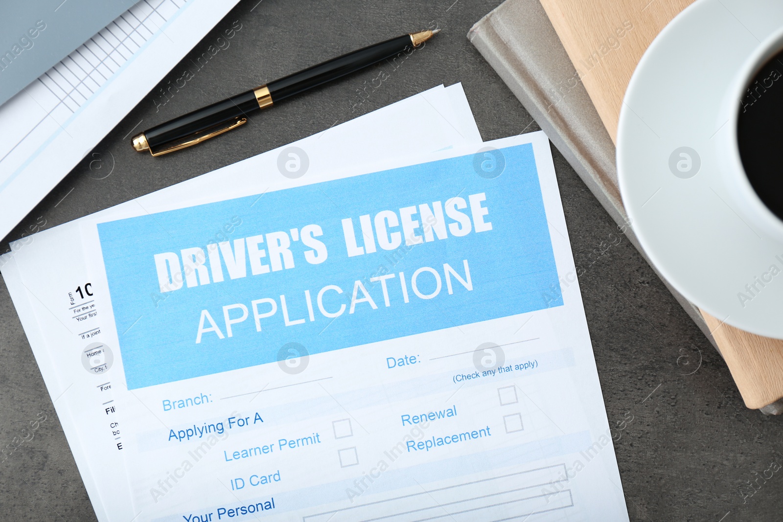 Photo of Driver's license application form and stationery on grey table, flat lay
