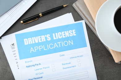 Driver's license application form and stationery on grey table, flat lay