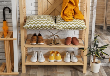 Stylish hallway interior with shoe rack near brick wall