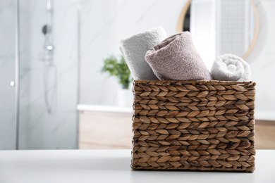 Photo of Wicker basket with clean soft towels in bathroom. Space for text