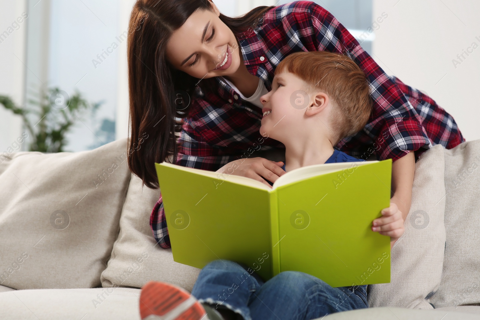 Photo of Happy mother reading book with her child at home