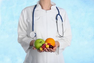 Female doctor with fresh products on light background. Cardiac diet