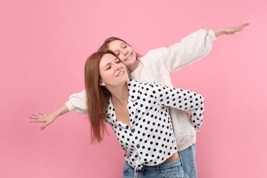 Happy mother with her cute daughter on pink background