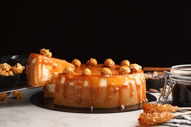 Photo of Taking piece of delicious caramel cheesecake with popcorn on light grey table