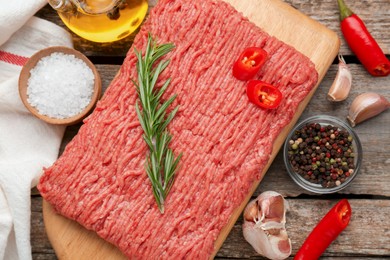 Raw fresh minced meat and ingredients on wooden table, flat lay