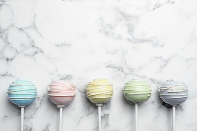 Sweet colorful cake pops on white background, flat lay. Space for text