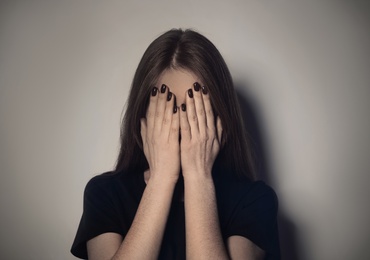 Photo of Upset young woman crying against light background