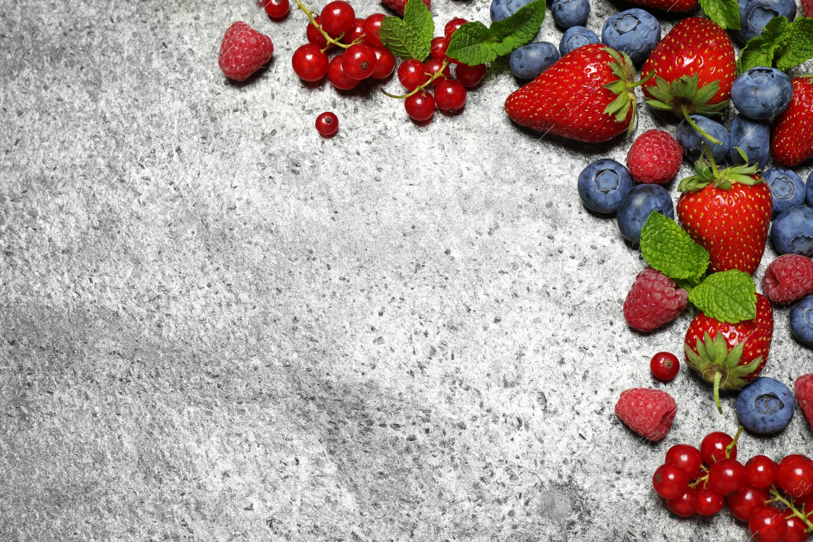 Photo of Different fresh berries on grey background, flat lay. Space for text